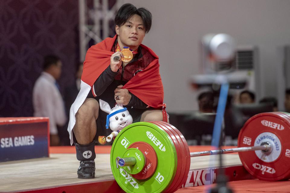 Lifter putra Indonesia Rahmat Erwin Abdullah menunjukkan medali emas yang berhasil diraihnya dari kelas 81 kg putra SEA Games 2023 di Taekwondo Hall, Olympic Complex, Phnom Penh, Kamboja, Senin (15/5/2023). 