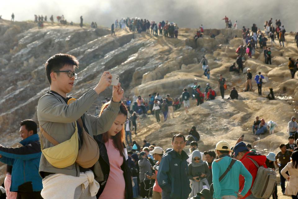 Pengunjung melihat kawah dari kaldera Gunung Ijen di Banyuwangi, Jawa Timur, Minggu (4/5/2023). TWA Ijen yang telah ditetapkan sebagai anggota UNESCO Global Geopark (UGG) itu ramai dikunjungi wisatawan domestik dan mancanegara saat liburan.