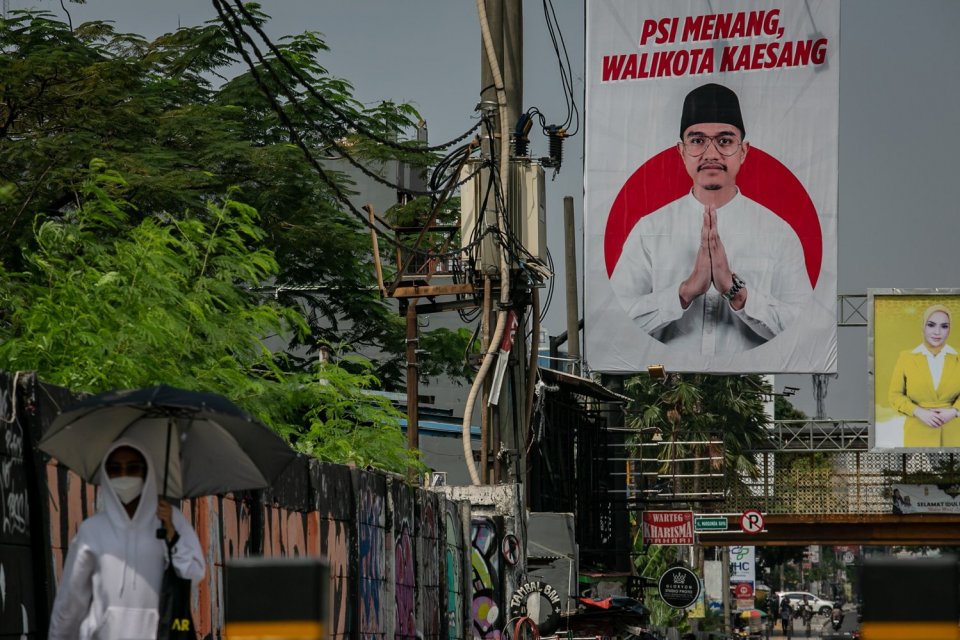 Warga melintas di jalur pedestrian dengan latar belakang baliho dukungan Partai Solidaritas Indoensia (PSI) untuk Kaesang Pangarep maju menjadi wali kota Depok, Depok, Jawa Barat, Selasa (13/6). 