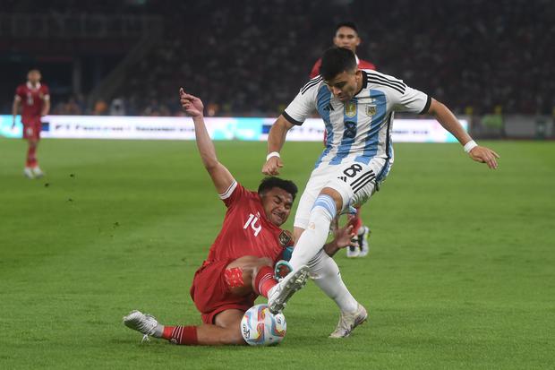 Pesepak bola Timnas Indonesia Asnawi Mangkualam (kiri) berebut bola dengan pesepak bola Timnas Argentina Marcos Javier Acuna (kanan) saat laga persahabatan FIFA Matchday di Stadion Utama Gelora Bung Karno, Jakarta, Senin (19/6/2023). TImnas Indonesia haru