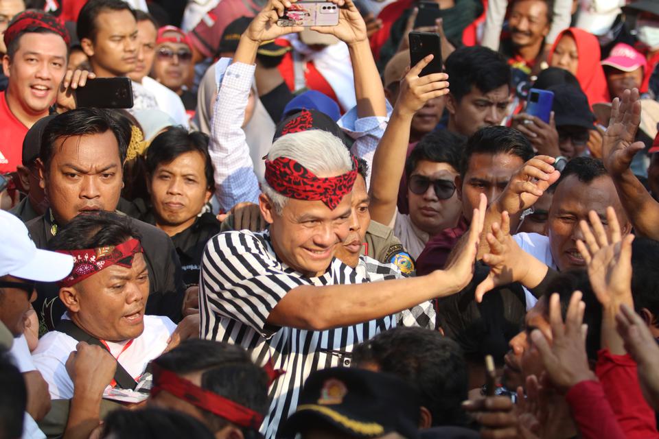 Bakal calon presiden dari PDI Perjuangan Ganjar Pranowo (tengah) menyapa warga saat menghadiri Gerak Jalan Kebangsaan di Nganjuk, Jawa Timur, Jumat (23/6/2023). Gerak jalan sore yang diselenggarakan relawan desa paguyuban sedulur Ganjar tersebut diikuti o