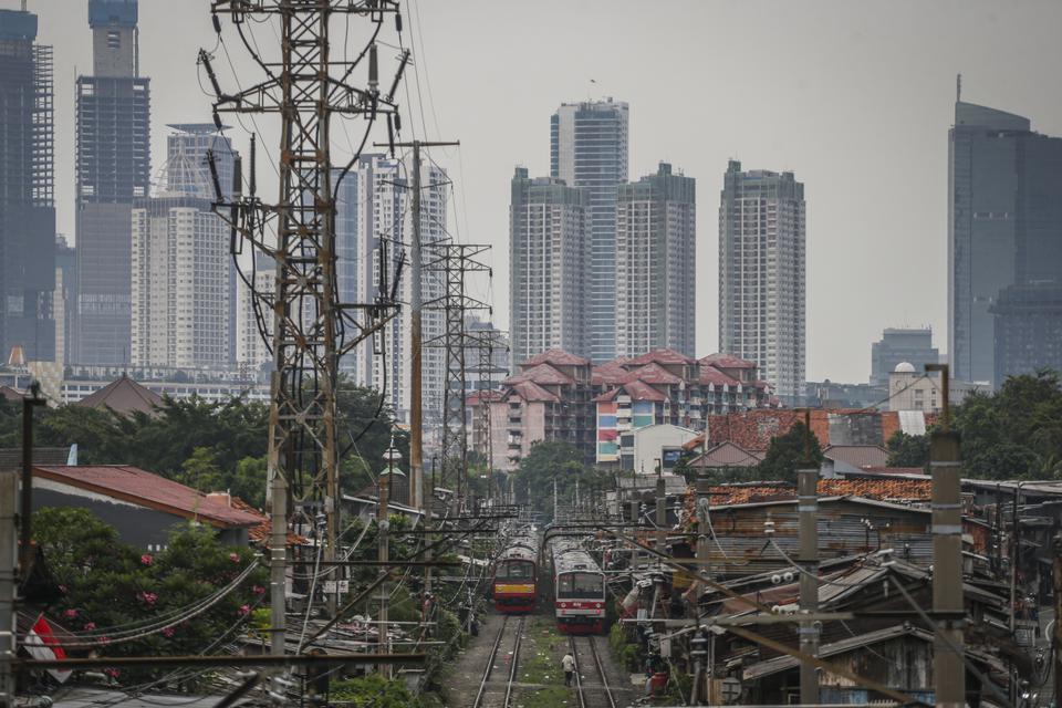 KRL Commuter Line melintas dengan latar belakang gedung bertingkat di Pejompongan, Jakarta, Selasa (27/6/2023). 