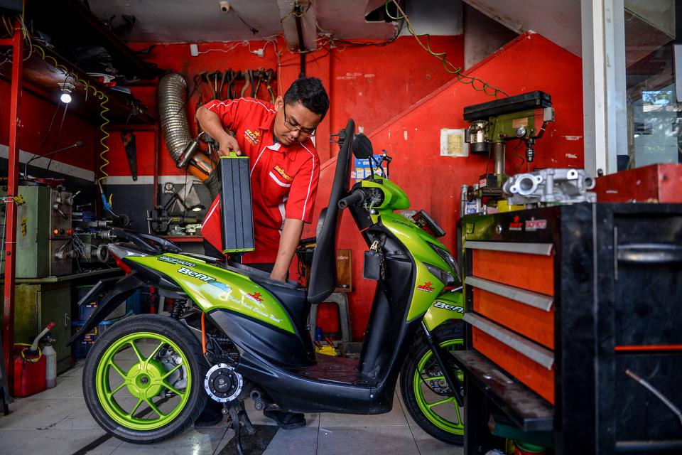 Mekanik melepas baterai motor bbm yang dikonversi ke motor listrik di bengkel Bacip Moto Shop di Bandung, Jawa Barat, Senin (3/7/2023). Bengkel Bacip Moto Shop binaan Bintang Racing Team tersebut merupakan bengkel resmi pemasangan, perawatan, pemeriksaan 