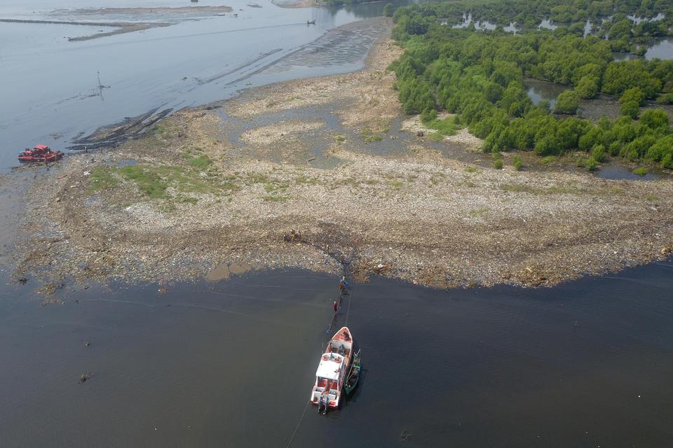 Foto udara petugas Penanganan dan Prasarana & Sarana Umum (PPSU) bersama petugas kebersihan dari Dinas Lingkungan Hidup (DLH) DKI Jakarta mengangkut sampah yang menumpuk di Hutan Mangrove Muara Angke, Jakarta Utara, Sabtu (15/7/2023). Menurut petugas seti