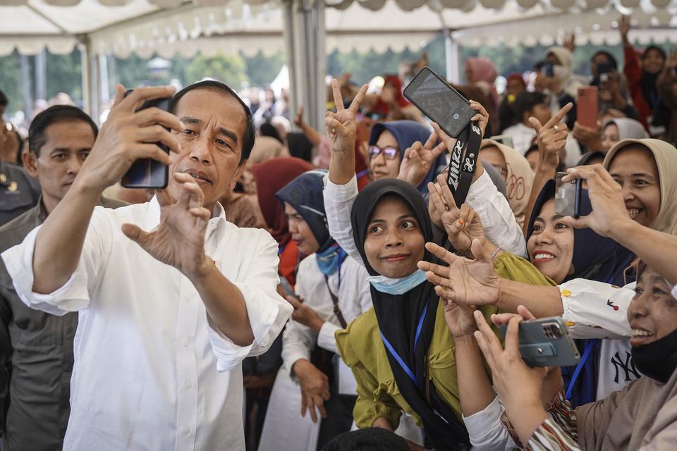 Presiden Joko Widodo (kiri) melakukan swafoto bersama warga saat mengunjungi Pasar Rakyat Kota Malang di Lapangan Rampal, Malang, Jawa Timur, Senin (24/7/2023). 