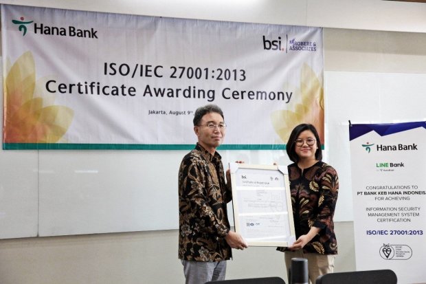 Sertifikat ini secara simbolis diterima oleh Direktur Utama Bank Hana Park Jong Jin dan diserahkan oleh Direktur Robere & Associates Indonesia Vera Anita sebagai partner dan perwakilan dari BSI pada Rabu (9/8) di Kantor Pusat Bank Hana, Jakarta. \