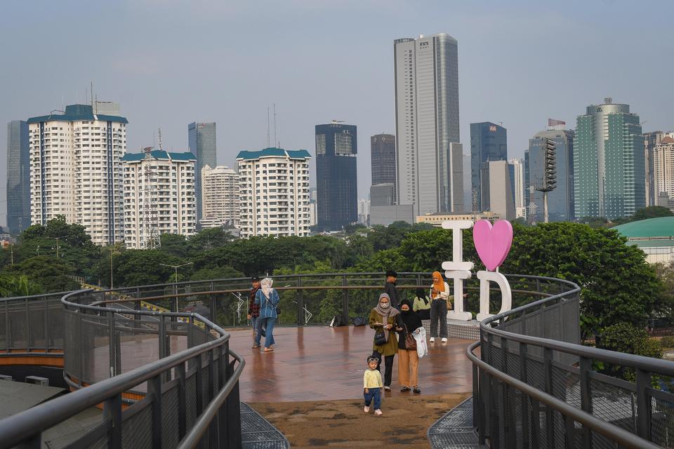 Sejumlah warga berjalan dengan latar belakang gedung-gedung perkantoran dan apartemen di Jakarta, Jumat (11/8/2023). 