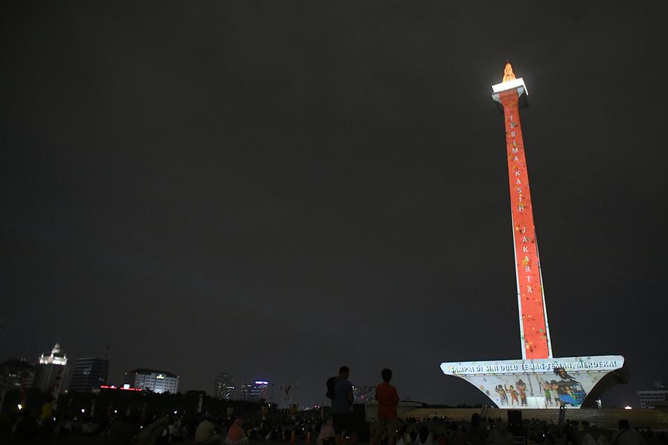 Pengunjung menyaksikan video mapping di Tugu Monas, Jakarta, Minggu (20/8/2023).