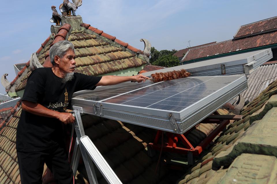 Seorang warga, Riyanto membersihkan panel pembangkit listrik tenaga surya (PLTS) di atas atap rumahnya di Kelurahan Kaliwungu, Kabupaten Jombang, Jawa Timur, Jumat (8/9/2023). Penggunaan PLTS berkapasitas 6 kWp itu mampu membantu menghemat biaya pengeluar