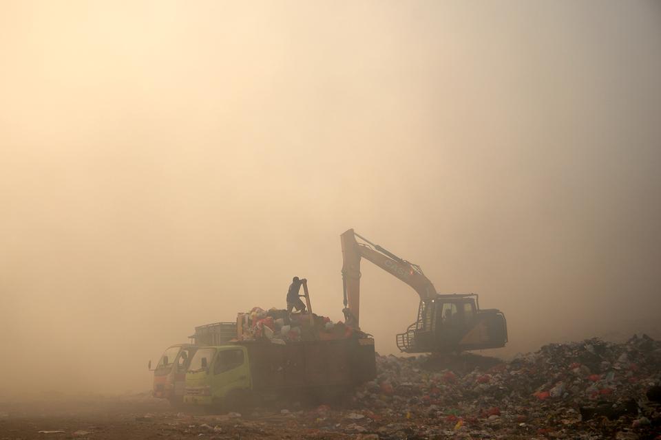 pekerja memindahkan tumpukan sampah yang belum terbakar ditengah kepulan asap tebal di Tempat Pembuangan Akhir (TPA) Sumompo, Manado, Sulawesi Utara, Selasa (2/10/2023). Pemerintah kota Manado menghimbau warga yang bermukim di sekitar lokasi TPA Sumompo u
