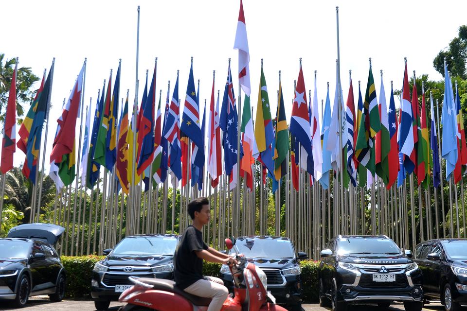 Warga melintasi bendera negara-negara pulau dan kepulauan serta organisasi internasional yang akan berpartisipasi dalam Archipelagic and Island States (AIS) Forum 2023 di Bali Nusa Dua Convention Center (BNDCC), Badung, Bali, Jumat (6/10/2023).