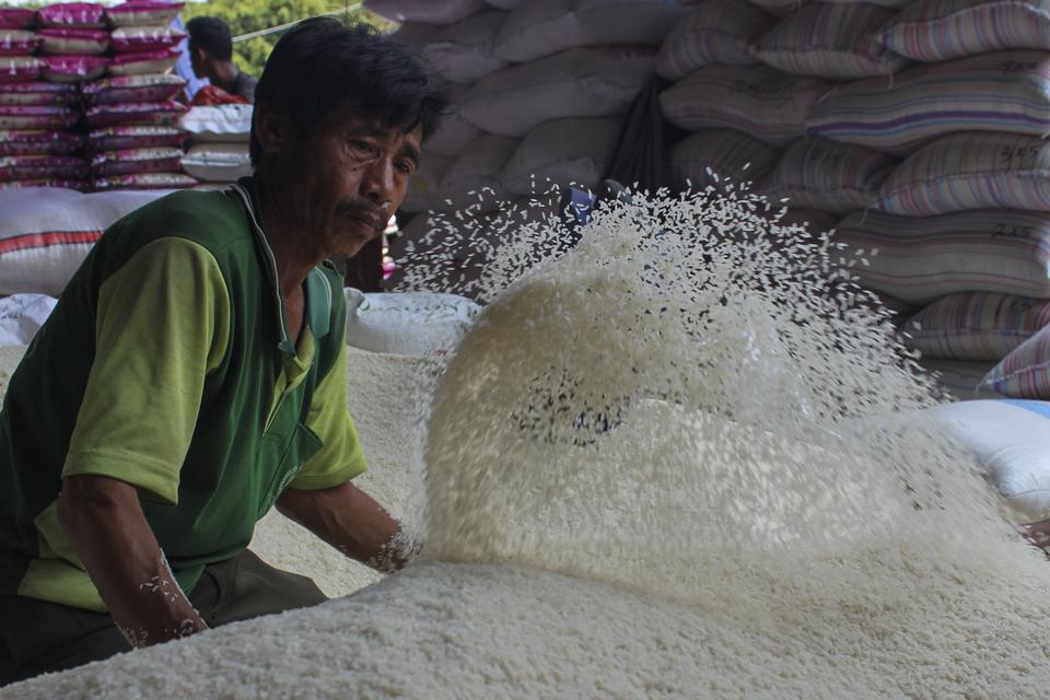 Pekerja membersihkan beras dari kotoran sebelum dimasukkan ke karung di salah satu toko di Pasar Induk Beras Cipinang, Jakarta Timur, Kamis (12/10/2023).
