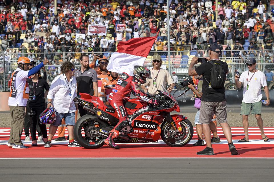 Pembalap Ducati Lenovo Team Enea Bastianini membawa bendera merah putih usai balapan MotoGP seri Pertamina Grand Prix of Indonesia 2023 di Pertamina Mandalika International Street Circuit, Lombok Tengah, NTB, Minggu (15/10/2023). Francesco Bagnaia berhasi
