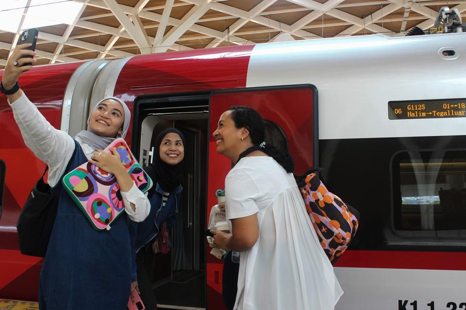 Sejumlah penumpang berswafoto sebelum menaiki Kereta Cepat Whoosh di Stasiun Kereta Cepat Halim, Jakarta, Senin (30/10/2023). PT Kereta Cepat Indonesia China (KCIC) menambah jumlah perjalanan dari semula 14 perjalanan per hari di bulan Oktober, menjadi 28