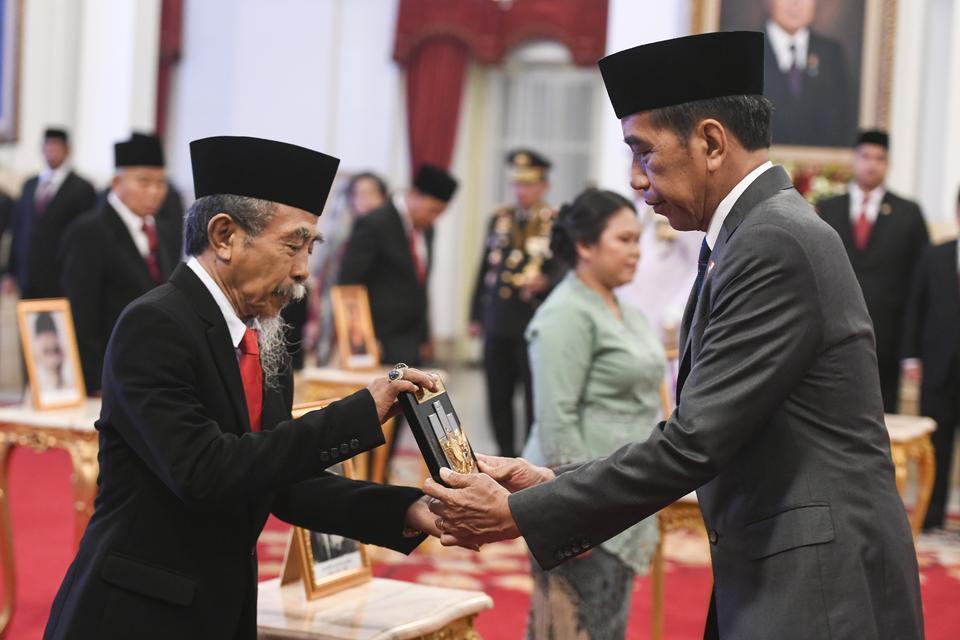 Presiden Joko Widodo (kanan) memberikan tanda gelar Pahlawan Nasional kepada ahli waris tokoh Ida Dewa Agung Jambe saat pemberian tanda gelar di Istana Negara, Jakarta, Jumat (10/11/2023). 