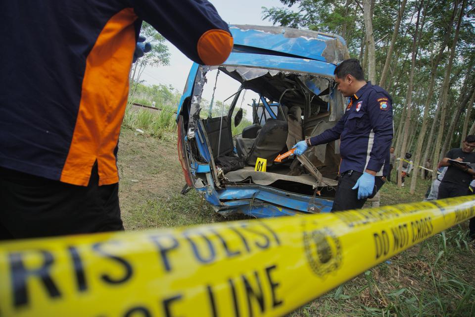 Petugas Ditreskrim Polda Jatim melakukan olah TKP kecelakaan mini bus bernomor polisi N 7646 T yang tertabrak kereta api (KA) Probowangi di Kecamatan Klakah, Lumajang, Jawa Timur, Senin (20/11/2023). Kecelakaan yang terjadi di perlintasan kereta tanpa pal