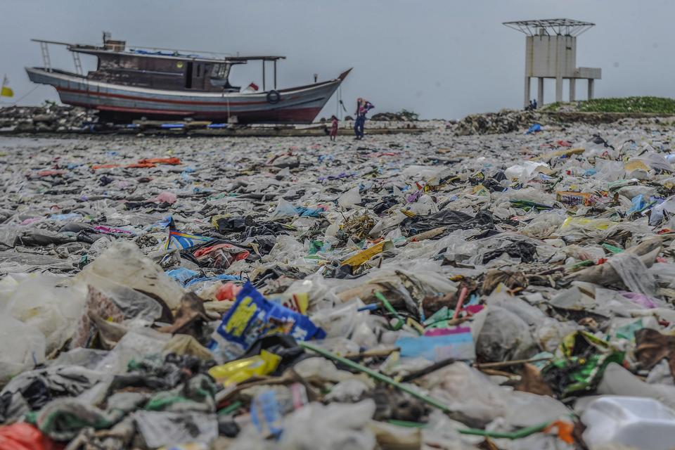 Warga berjalan diatas tumpukkan sampah plastik di Pantai Labuan, pandeglang, Banten, Selasa (12/12/2023). Kementerian Koordinasi Bidang Kemaritiman dan Investasi (Kemenko Marves) melalui PP Nomor 83 Tahun 2018 tentang Penanganan Sampah Laut menargetkan pe