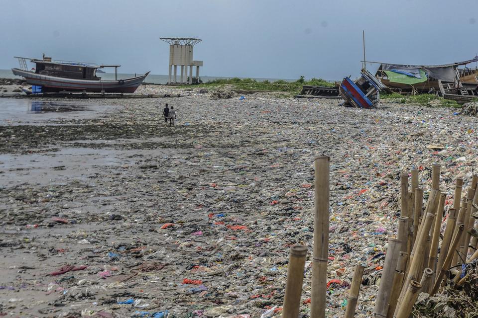 Warga berjalan diatas tumpukkan sampah plastik di Pantai Labuan, pandeglang, Banten, Selasa (12/12/2023). Kementerian Koordinasi Bidang Kemaritiman dan Investasi (Kemenko Marves) melalui PP Nomor 83 Tahun 2018 tentang Penanganan Sampah Laut menargetkan pe