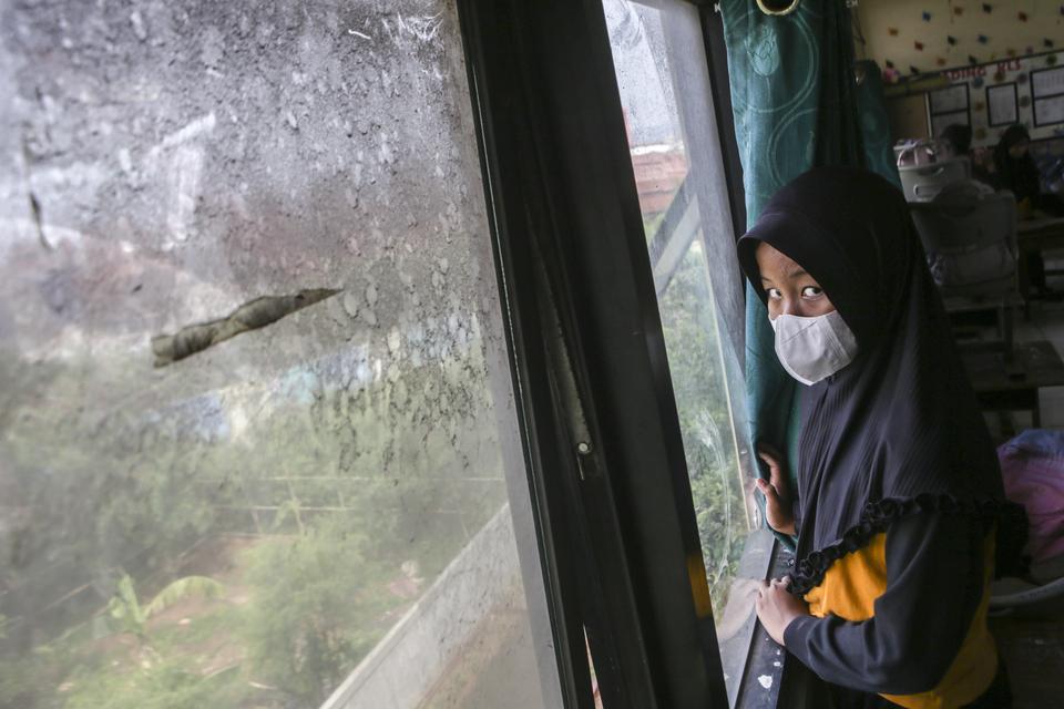 Seorang murid berdiri di dekat jendela yang kotor oleh debu di SD Negeri 05 Marunda, Jakarta, Rabu (13/12/2023). Warga setempat mengeluhkan paparan debu setelah kembali beroperasinya bongkar muat salah satu perusahaan di Pelabuhan Marunda, Jakarta Utara y