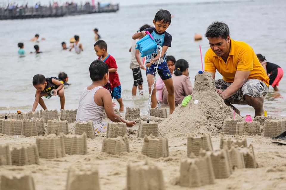 Pengunjunh bermain pasir saat berwisata di Pantai Lagoon, Ancol, Jakarta, Selasa (26/12/2023). Pengelola Taman Impian Jaya Ancol mencatat hingga Selasa (26/12) pukul 13.00 WIB, jumlah pengunjung mencapai 18.000 orang pada libur Natal 2023.