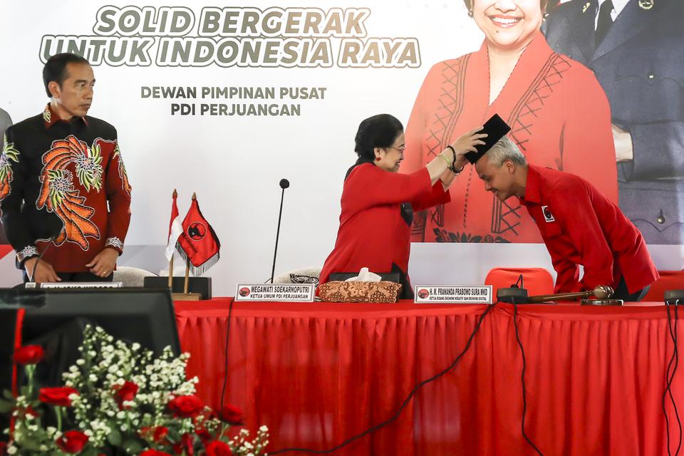 Ketua Umum PDI Perjuangan Megawati Soekarnoputri (tengah) menyematkan peci kepada calon Presiden 2024 yang diajukan PDI Perjuangan Ganjar Pranowo (kanan) disaksikan Presiden Joko Widodo (kiri) di Istana Batu Tulis, Bogor, Jawa Barat, Jumat (21/4/2023).
