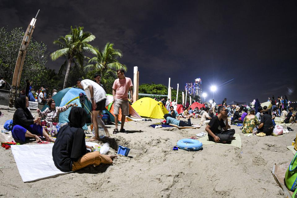 Sejumlah warga menunggu malam pergantian tahun di Pantai Lagoon, Taman Impian Jaya Ancol, Jakarta, Minggu (31/12/2023). Pantai di Ancol menjadi salah satu destinasi favorit warga Jakarta dan daerah-daerah lainnya untuk menghabiskan malam pergantian tahun 
