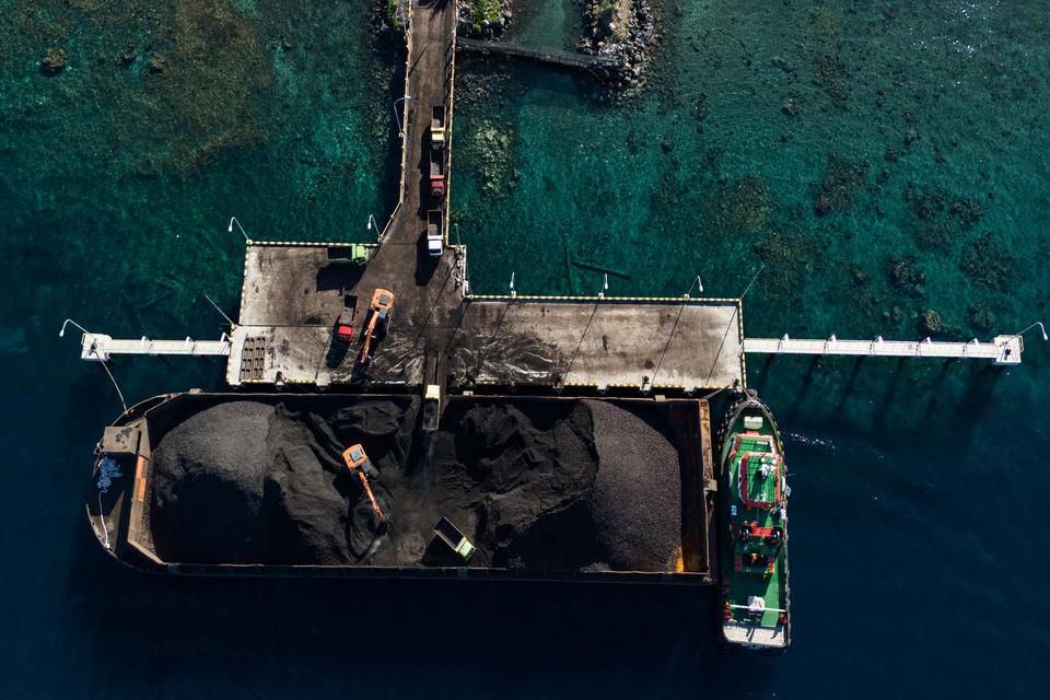 Foto udara pekerja mengoperasikan alat berat saat bongkar muat batu bara ke dalam truk yang didatangkan dari Samarinda di Pelabuhan PLTU Tidore Kepulauan, Maluku Utara, Kamis (4/1/2023). Kementerian Energi dan Sumber Daya Mineral (ESDM) mencatat alokasi p