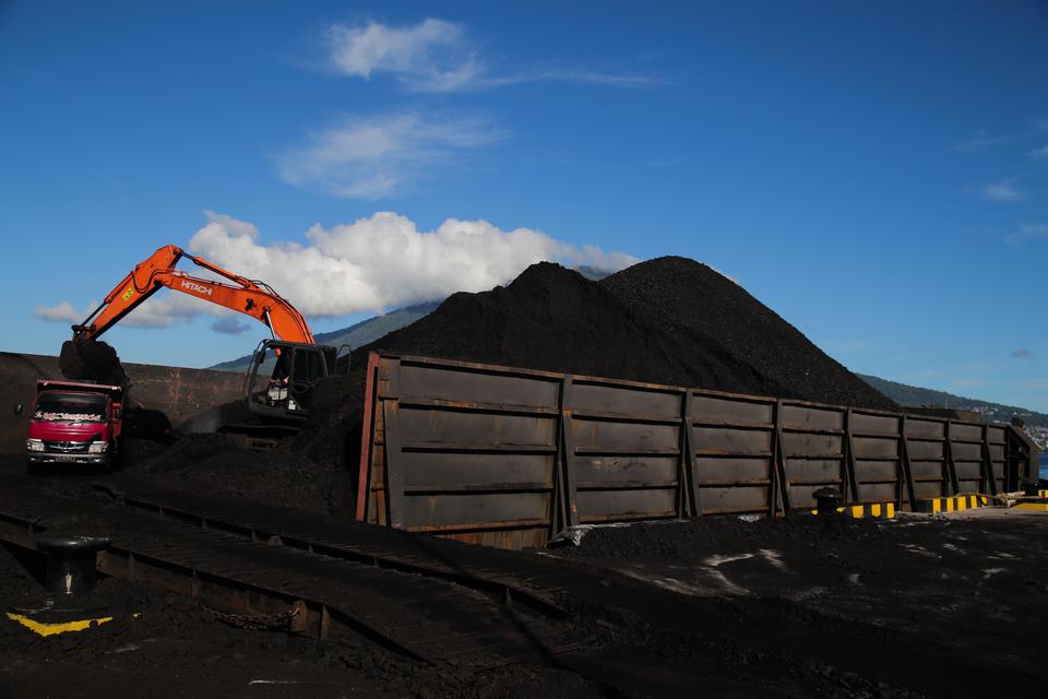 Pekerja mengoperasikan alat berat saat bongkar muat batu bara ke dalam truk yang didatangkan dari Samarinda di Pelabuhan PLTU Tidore Kepulauan, Maluku Utara, Kamis (4/1/2023). Kementerian Energi dan Sumber Daya Mineral (ESDM) mencatat realisasi produksi b