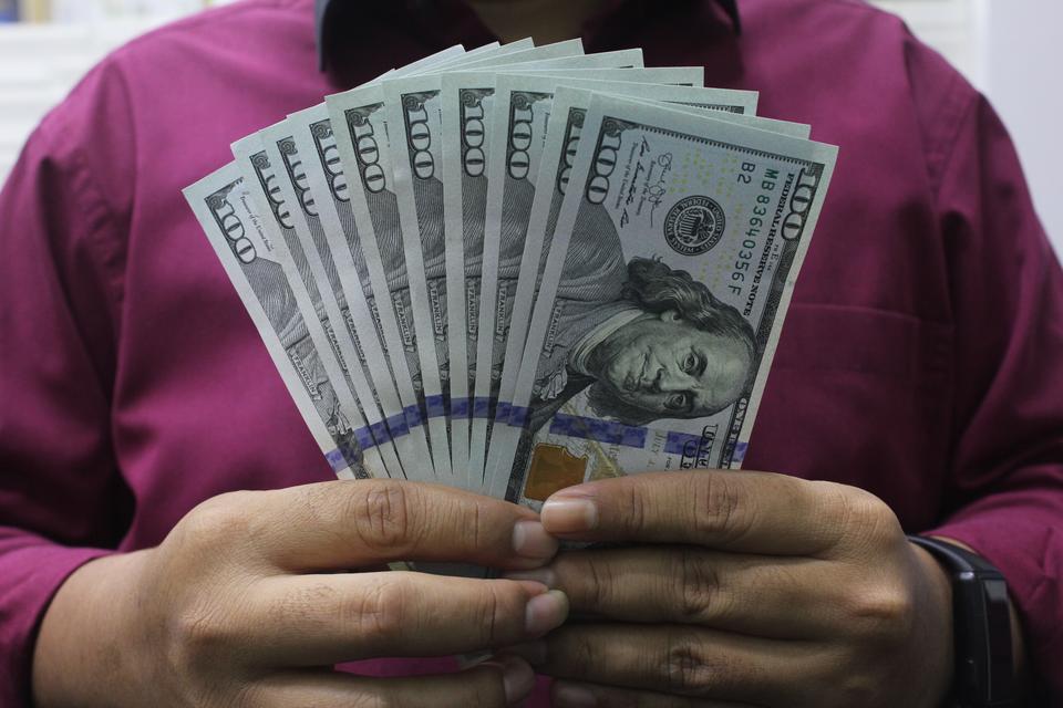 Petugas menunjukkan sejumlah lembaran 100 dolar Amerika Serikat di Dolarasia Money Changer Cibubur, Bekasi, Jawa Barat, Senin (8/1/2024). Bank Indonesia (BI) mencatat aliran modal asing masuk bersih di pasar keuangan domestik selama periode 2-4 Januari 20