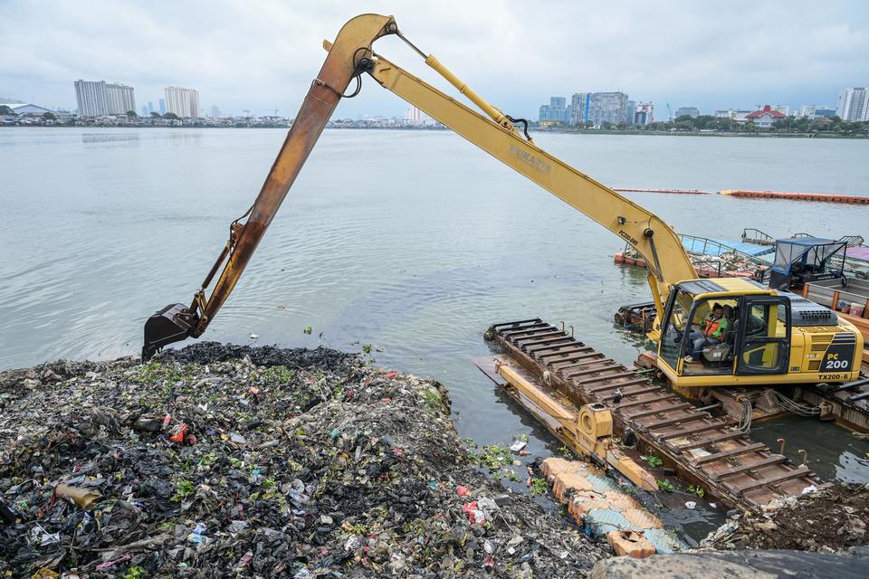 Petugas Unit Penanganan Sampah Badan Air DInas Lingkungan Hidup DKI Jakarta mengoperasikan alat berat membersihkan Waduk Pluit dari sampah, di Jakarta, Senin (5/2/2024). 