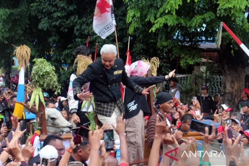 Calon presiden nomor urut 3 Ganjar Pranowo dan istrinya Atiqoh Ganjar Pranowo menaiki gerobak sapi dalam kampanye akbar di Solo, Jawa Tengah, pada Sabtu (10/2).