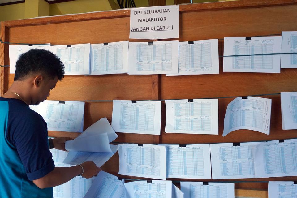 Warga mencari nama pada papan Daftar Pemilih Tetap (DPT) di Kelurahan Malabutor Kota Sorong, Papua Barat Daya, Selasa (13/2/2024).