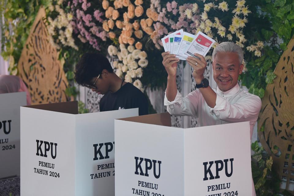 Calon presiden nomor urut 3 Ganjar Pranowo (kanan) menunjukkan surat suara didampingi anaknya Alam Ganjar (kiri) sebelum mencoblos di TPS 11 Lempongsari, Semarang, Jawa Tengah, Rabu (14/2/2024). 