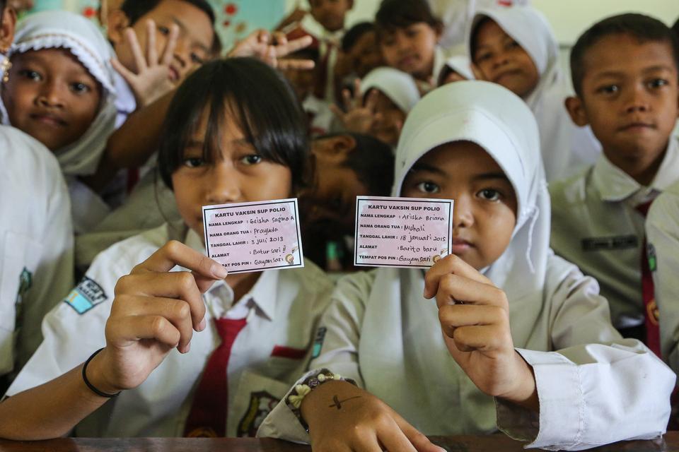 Sejumlah siswa menunjukkan kartu vaksinasi usai mendapatkan tetesan vaksin polio jenis imunisasi novel Oral Polio Vaccine Type 2 (nOPV2) kepada seorang siswa di SDN Sawah Besar 2, Semarang, Jawa Tengah, Senin (19/2/2024). Kementerian Kesehatan menggelar S