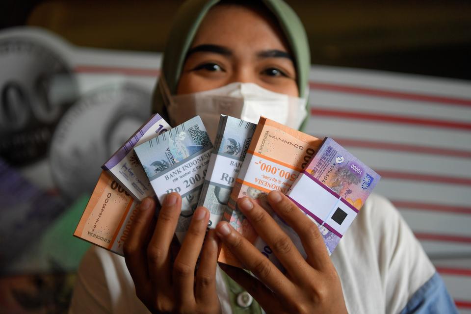 Warga menunjukkan uang rupiah baru pecahan kecil yang telah ditukarkan dari mobil kas keliling Bank Indonesia (BI) di Pasar Pramuka, Jakarta, Senin (18/3/2024). Bank Indonesia (BI) menyiapkan 4.713 titik penukaran uang rupiah baru layak edar, untuk period