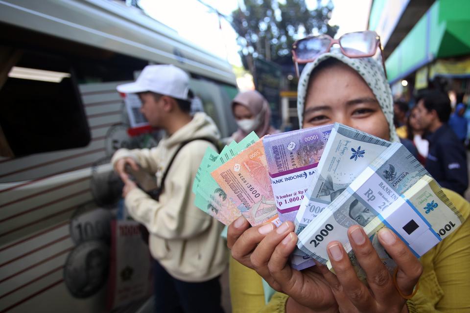 Warga menunjukan uang rupiah baru yang baru saja ditukarkan pada mobil kas keliling Bank Indonesia (BI) di Pasar Palmerah, Jakarta, Senin (18/3/2024). Layanan penukaran uang Rupiah melalui kas keliling merupakan wujud komitmen Bank Indonesia dalam member
