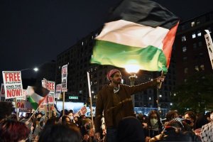 Seorang pria mengibarkan bendera Palestina dalam aksi unjuk rasa pro-Palestina yang digelar di luar Universitas Columbia di New York, Amerika Serikat