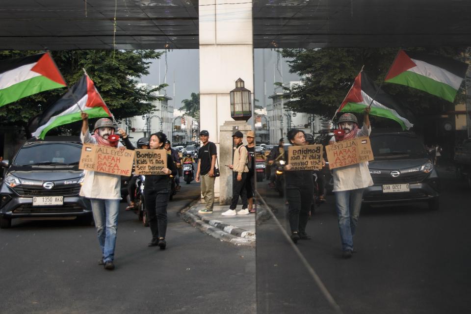 Seniman yang tergabung dalam Bandung Spirit of Palestine mengibarkan bendera Palestina saat aksi peringatan Hari Palang Merah Internasional (The International Federation of Red Cross and Red Crescent Societies) di Bandung, Jawa Barat, Rabu (8/5/2024). 