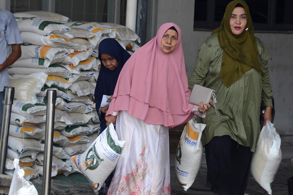 Keluarga penerima manfaat (KPM) membawa bantuan sosial pangan beras saat berlangsung penyaluran di kantor PT Pos Cabang Utama Banda Aceh, Aceh, Kamis (9/5/2024). Pemerintah kembali menyalurkan bantuan pangan beras 10 kilogram dari cadangan beras pemerint