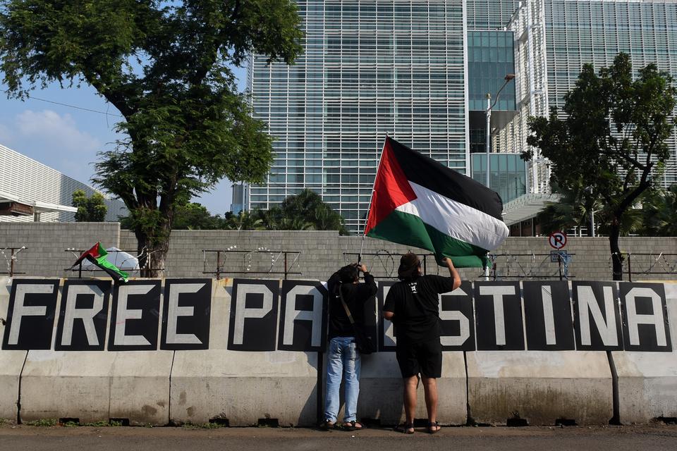 Dua pengunjuk rasa memasang bendera saat melakukan aksi solidaritas untuk rakyat Palestina di depan Kedutaan Besar Amerika Serikat, Jakarta, Jumat (10/5/2024). 