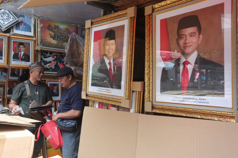 Pedagang melayani pembeli foto Presiden dan Wakil Presiden terpilih, Prabowo Subianto-Gibran Rakabuming Raka di Pasar Baru, Jakarta.