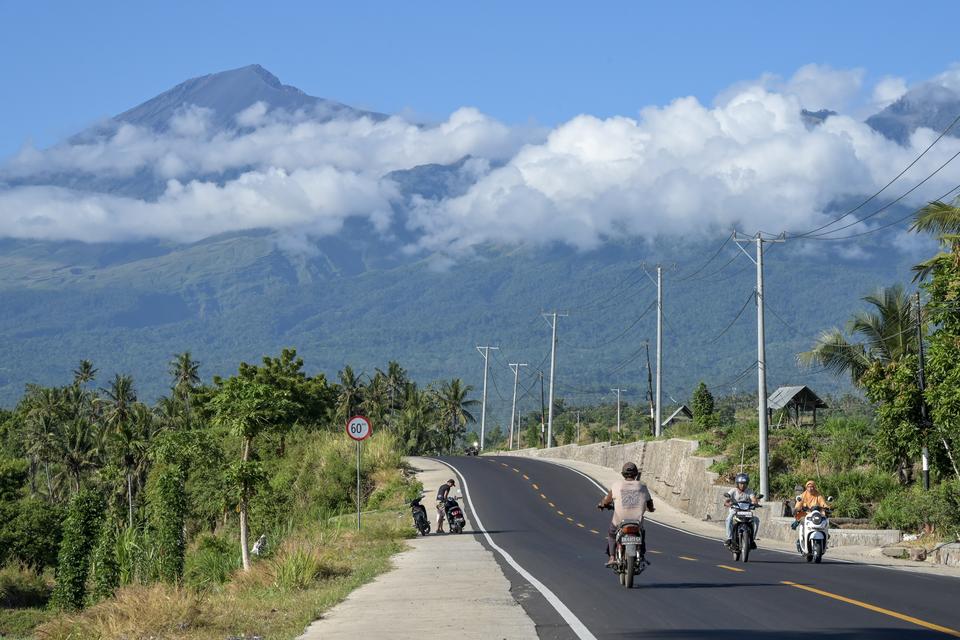 Pengendara sepeda motor melintas di jalan yang baru selesai ditingkatkan menuju kawasan wisata Gunung Rinjani di Senaru, Kecamatan Bayan, Tanjung Lombok Utara, NTB, Sabtu (8/6/2024). 