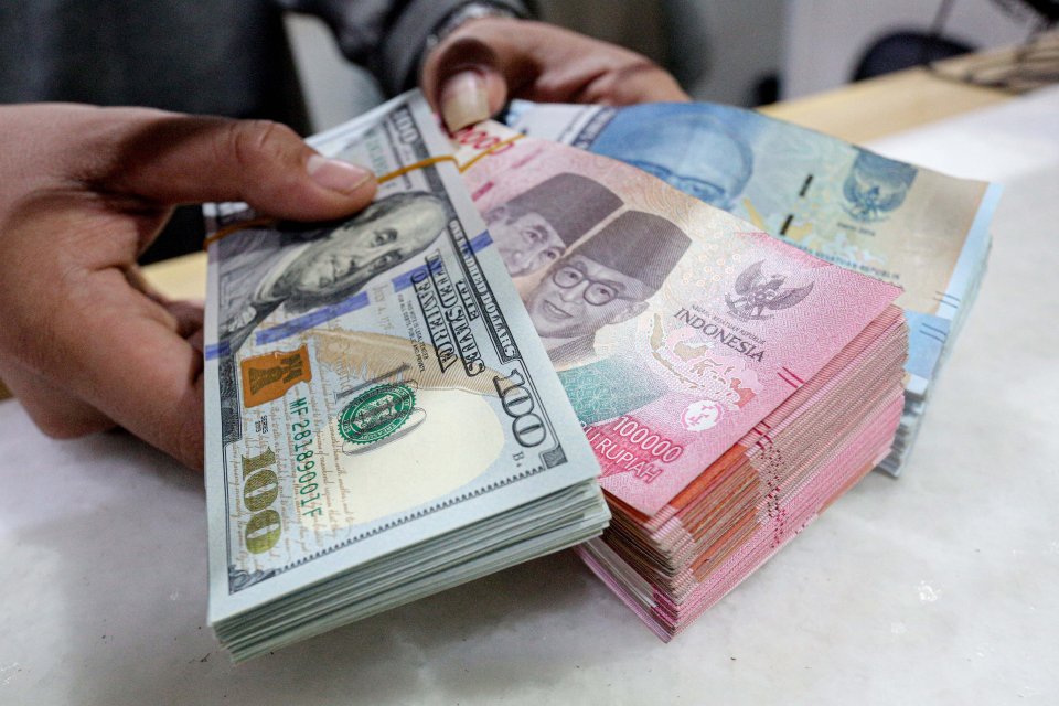 Petugas menunjukkan uang dolar AS dan rupiah di Dewata Inter Money Changer, Jakarta, Jumat (14/6/2024). 