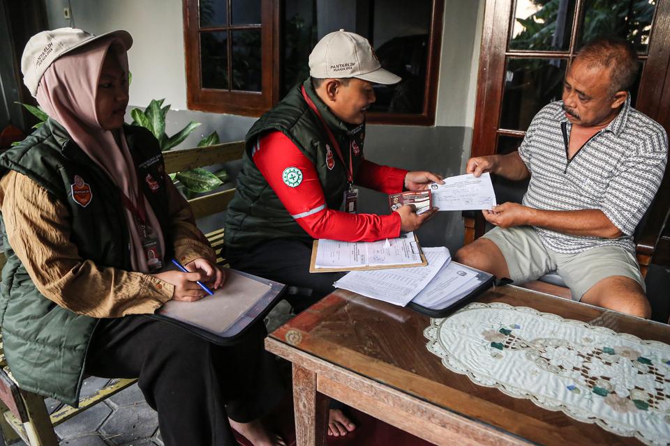 Petugas Pemutakhiran Data Pemilih (Pantarlih) KPU memberikan surat pemutakhiran data saat pencocokan dan penelitian (coklit) data pemilih di kawasan Jalan Muwardi, Semarang, Jawa Tengah, Selasa (9/7/2024). 