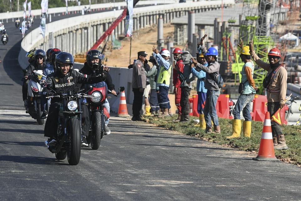 Presiden Joko Widodo (depan) bersama sejumlah influencer media sosial menyapa pekerja saat mengendarai motor melewati Jalan Tol IKN di Balikpapan, Kalimantan Timur, Minggu (28/7/2024). 