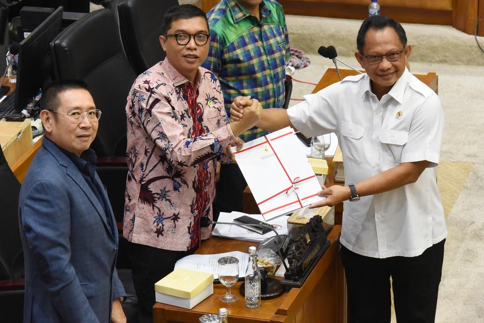 Menteri Dalam Negeri Tito Karnavian menyerahkan berkas pandangan pemerintah kepada Wakil Ketua Badan Legislasi DPR, Achmad Baidowi dalam rapat pengambilan keputusan pembahasan RUU Pilkada di Kompleks Parlemen, Senayan, Jakarta, Rabu (21/8/2024).