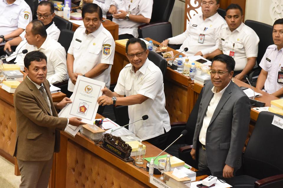 Menteri Dalam Negeri Tito Karnavian (kedua kanan) menerima berkas pandangan mini Fraksi Partai Gerindra dari anggota Baleg Fraksi Gerindra Habiburokhman (kiri) disaksikan Menteri Hukum dan HAM Supratman Andi Agtas (kanan) dalam rapat pengambilan keputusan