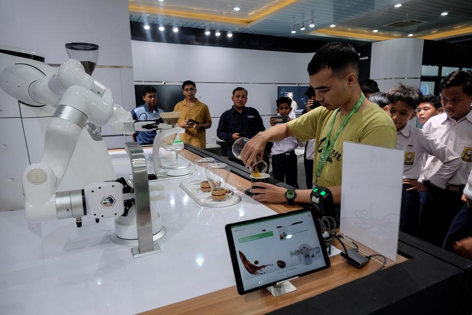 Sejumlah siswa mengamati proses penyeduhan kopi oleh robot barista dengan kecerdasan buatan (AI) yang dipamerkan di Indosat AI Experience Center, Solo Technopark, Solo, Jawa Tengah, Rabu (4/9/2024). AI Experience Center pertama di Indonesia tersebut untuk