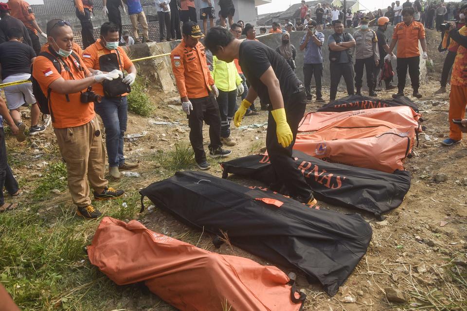 Sejumlah polisi memeriksa kantong-kantong berisi tujuh jenazah laki laki yang ditemukan mengambang di Kali Bekasi, Pondok Gede Permai, Jatiasih, Kota Bekasi, Minggu (22/9/2024). 