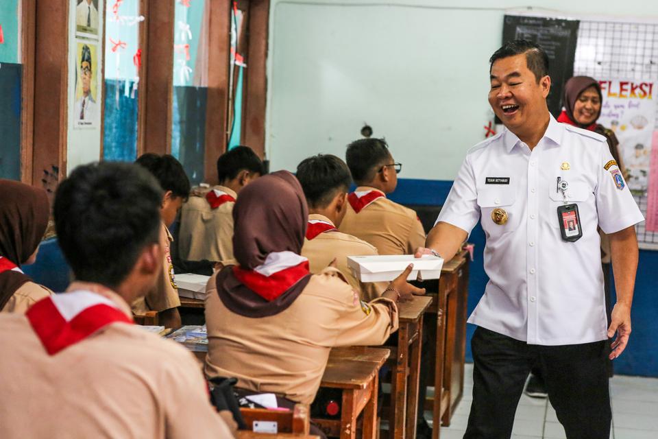 Pj Gubernur DKI Jakarta Teguh Setyabudi (kanan) memberikan makanan kepada siswa saat pelaksanaan uji coba makan bergizi di SMPN 270 Kelapa Gading, Jakarta Utara, Rabu (23/10/2024). 